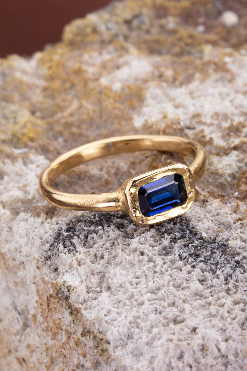 Gold ring with a blue gemstone on a textured stone surface