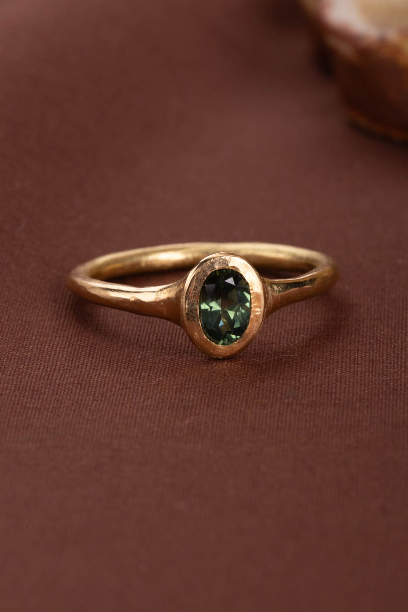 Gold ring with a green gemstone on a brown background