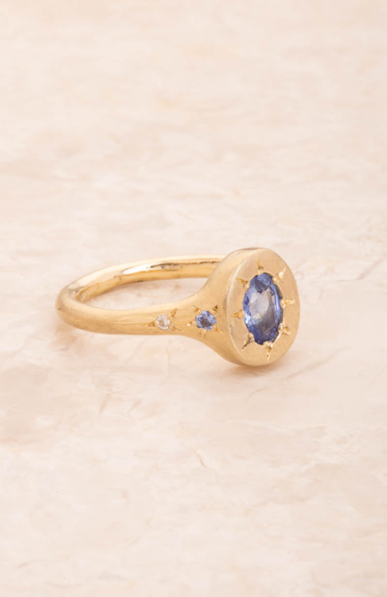 Gold ring with a blue gemstone on a beige background