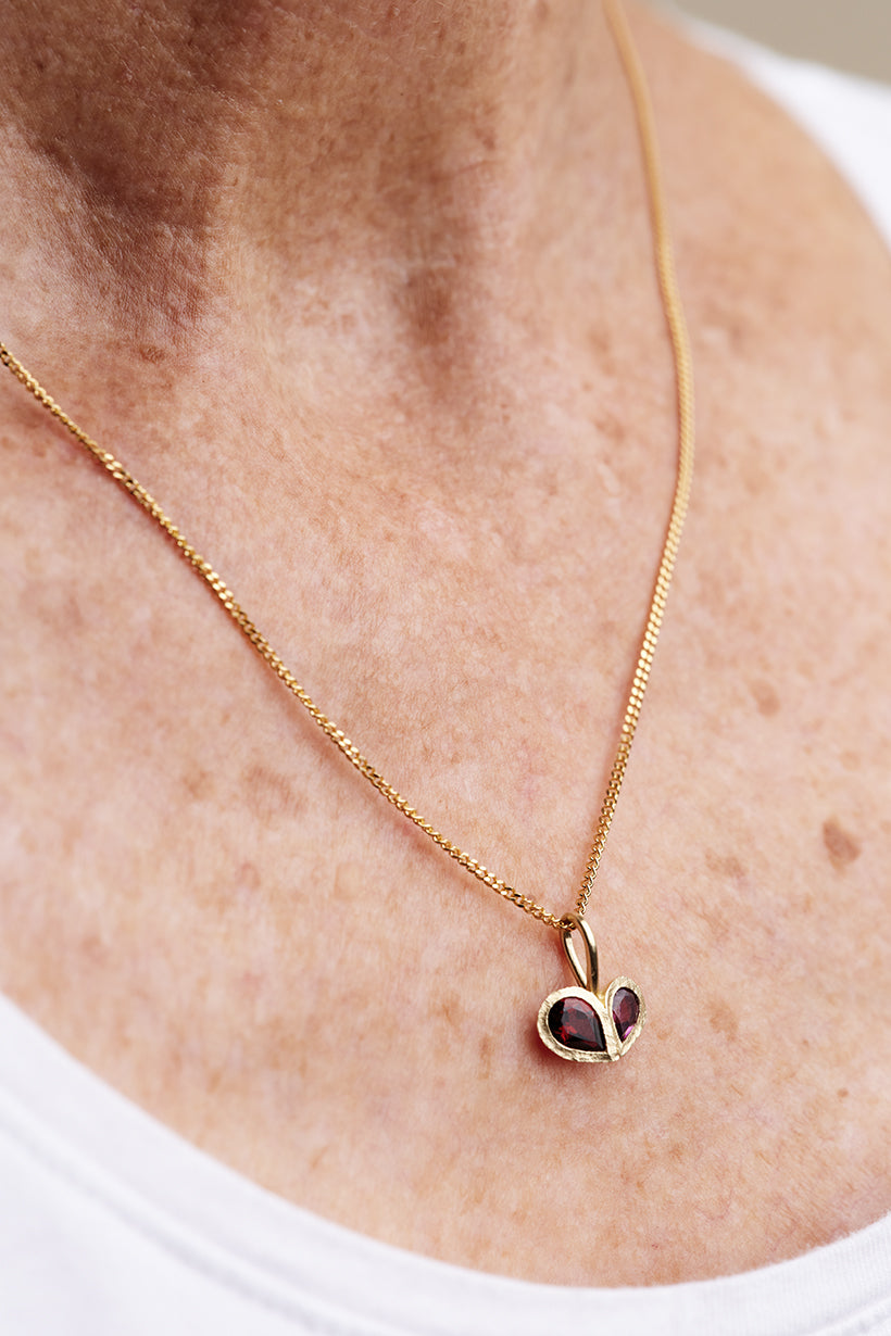 Gold necklace with a heart-shaped pendant on a person's neck