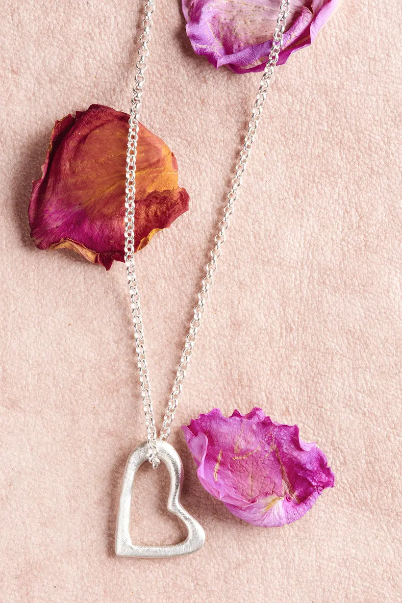 Close-up of sterling silver Heartline Necklace resting on linen – recycled silver jewellery inspired by petals and connection