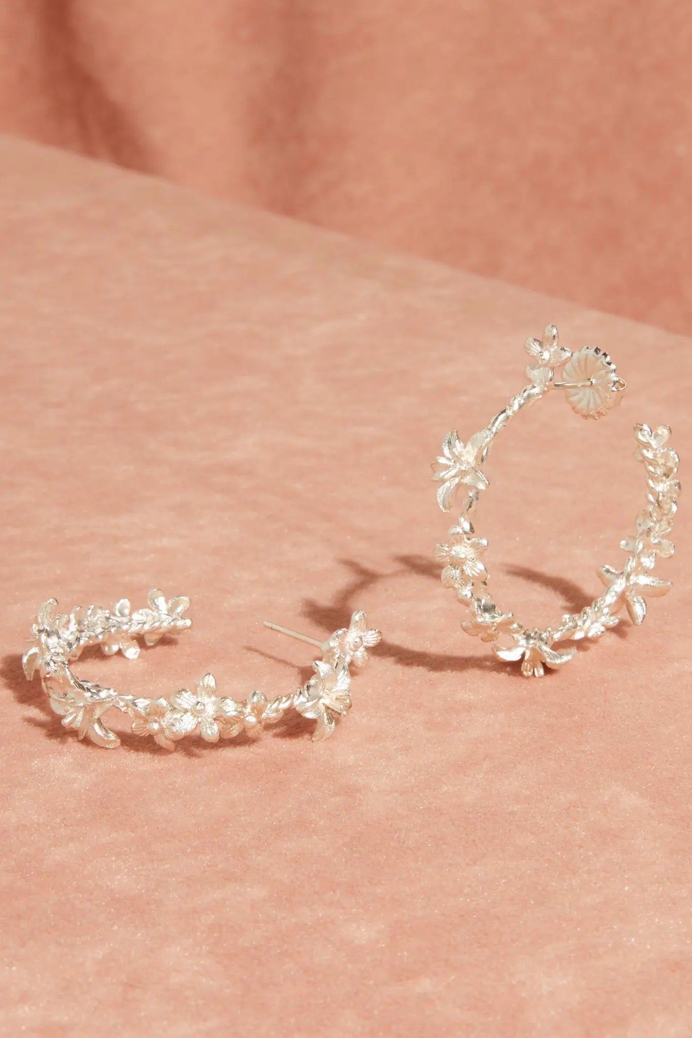 Pair of sterling silver garland hoops on a pink velvet background