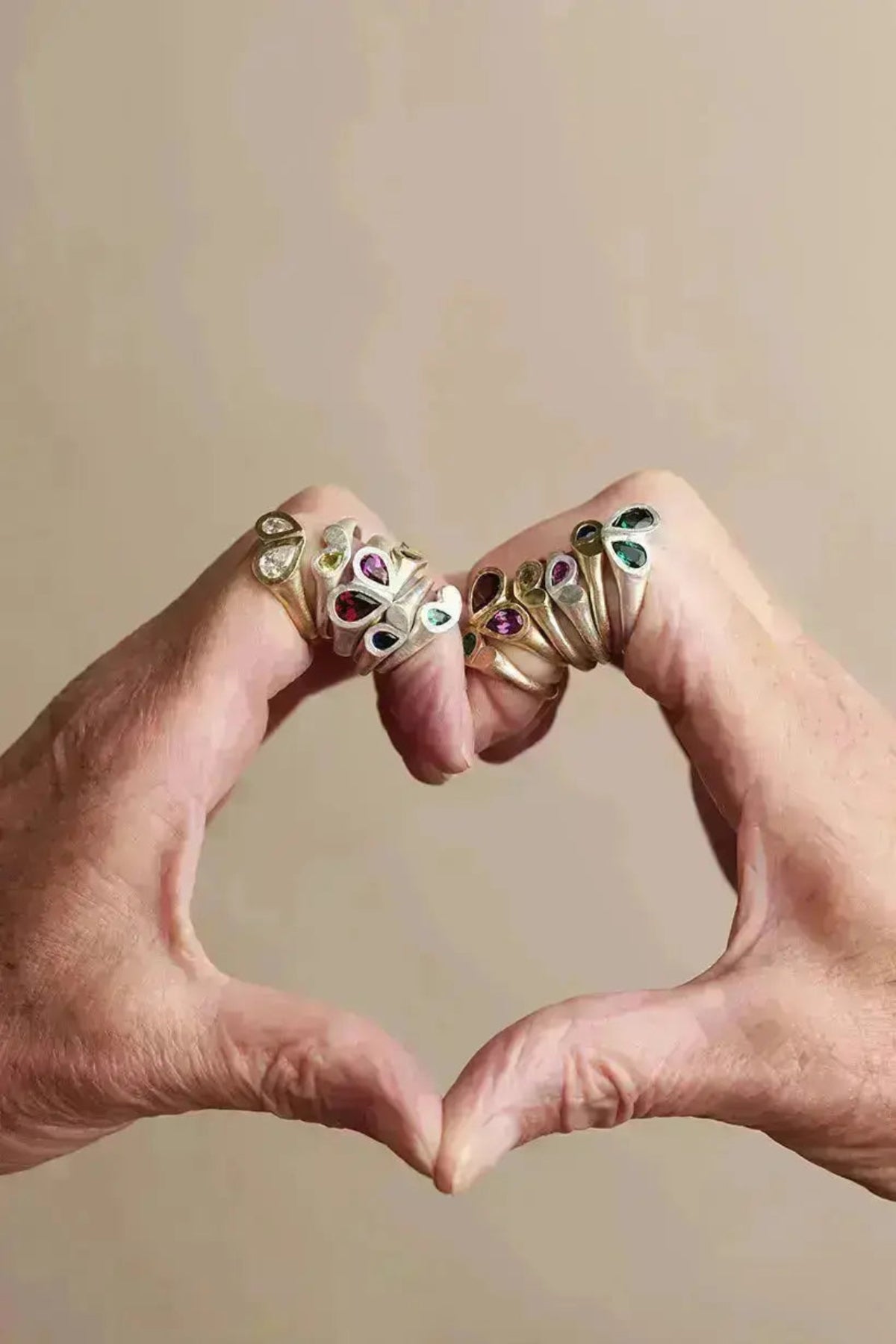 Model makes a heart shape with hands wearing all rings form the petal hearts collection.