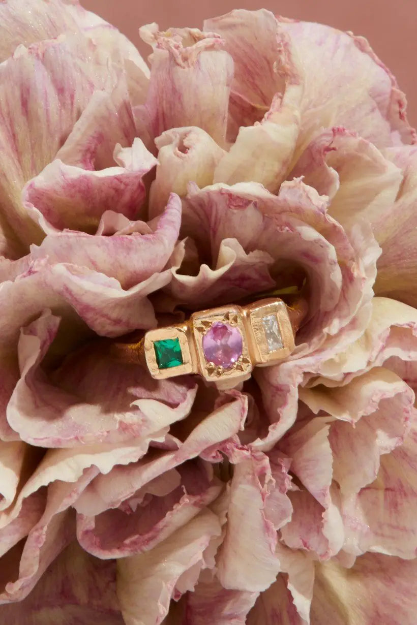 Stepping Stones ring, vibrant sapphire, emerald and diamond set in organic textured gold sitting a flower