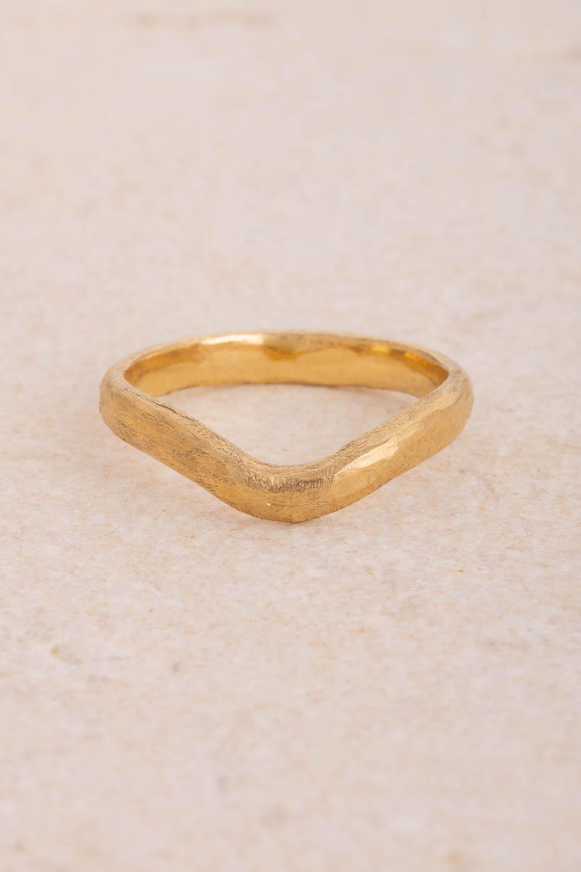 Curved Breeze 3mm fitted wedding band in textured recycled gold, gently arched to sit snugly beside an engagement ring, handmade in Melbourne, front view on limestone