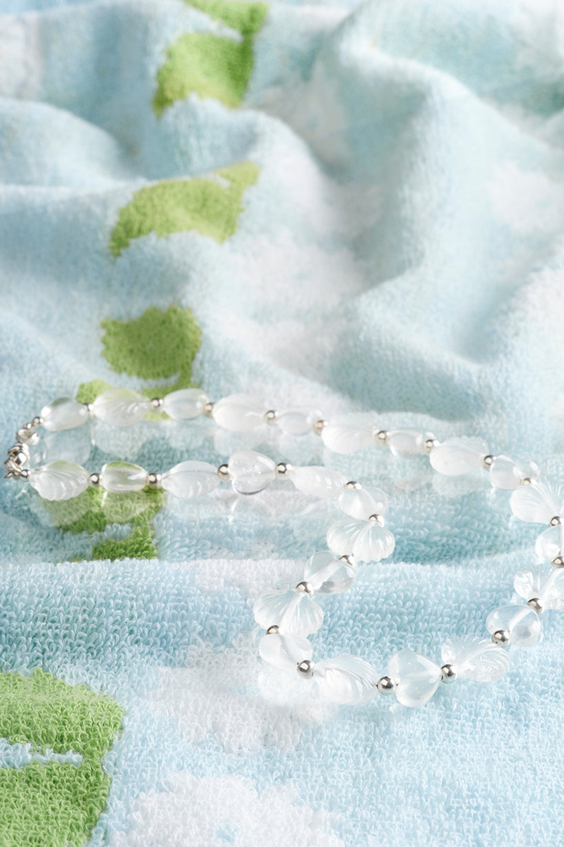 White beaded Daydream necklace on a floral fabric background