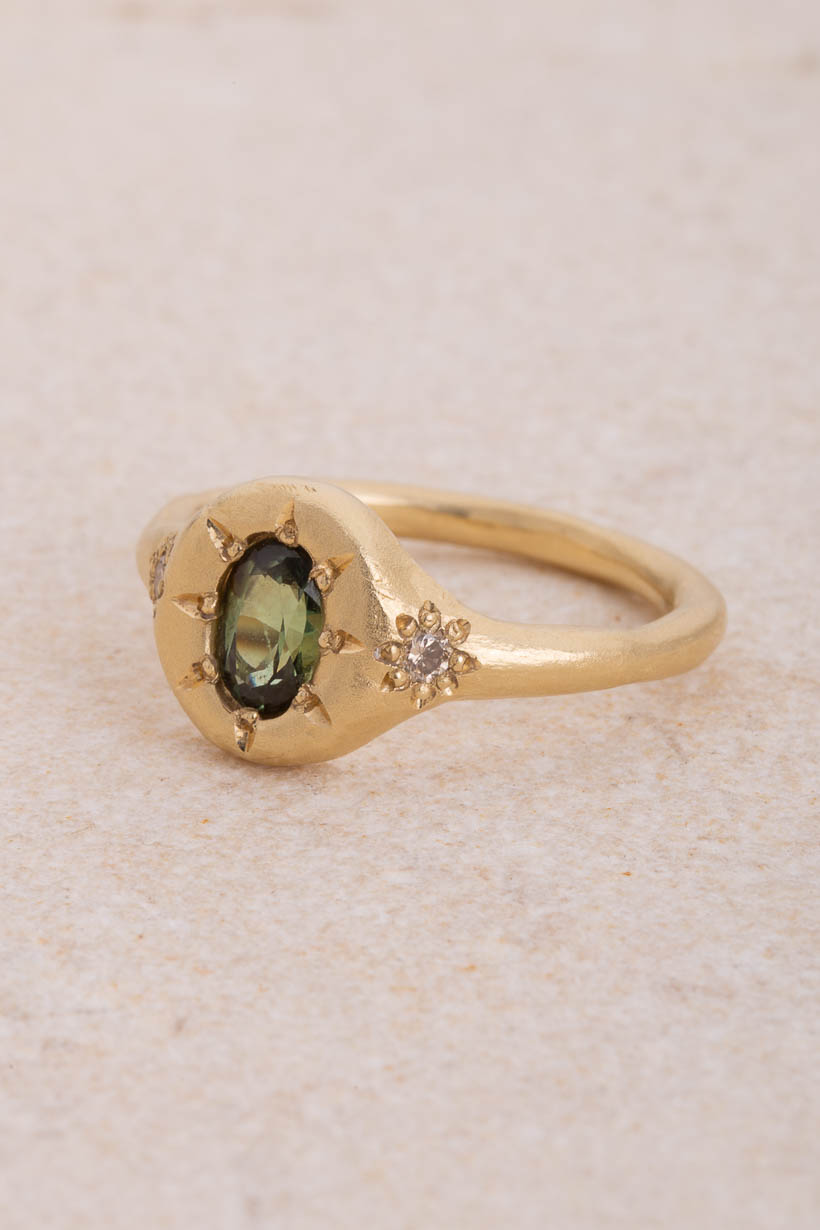 Side view of the Monet’s Garden ring showing the green Australian sapphire in a star setting and a champagne diamond flower on the shoulder