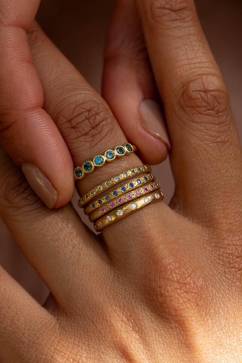 Teal Australian sapphire Gumnut wedding band stacked with the Dewfall diamond eternity band and a Rosette ring on the hand, Ada Hodgson