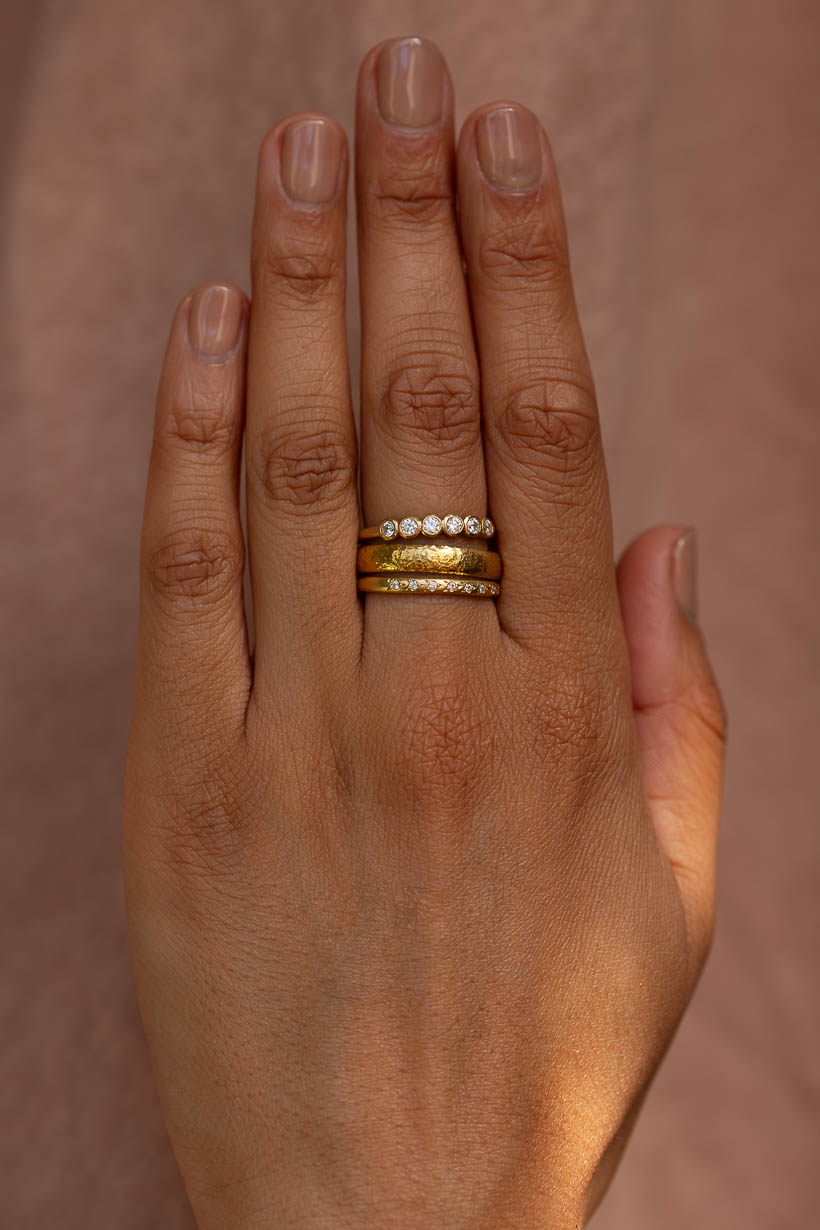 Ring stack on hand: the Gumnut diamond wedding band with the 4mm Moraine ring and the Rosette ring with white diamonds, all in recycled gold
