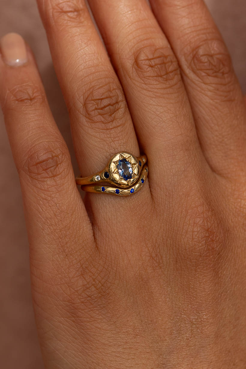 Curved Rosette ring with blue Australian sapphires worn on the hand, curving snugly beside a low profile engagement ring, the Monet's Garden ring with a natural light blue Ceylon sapphire