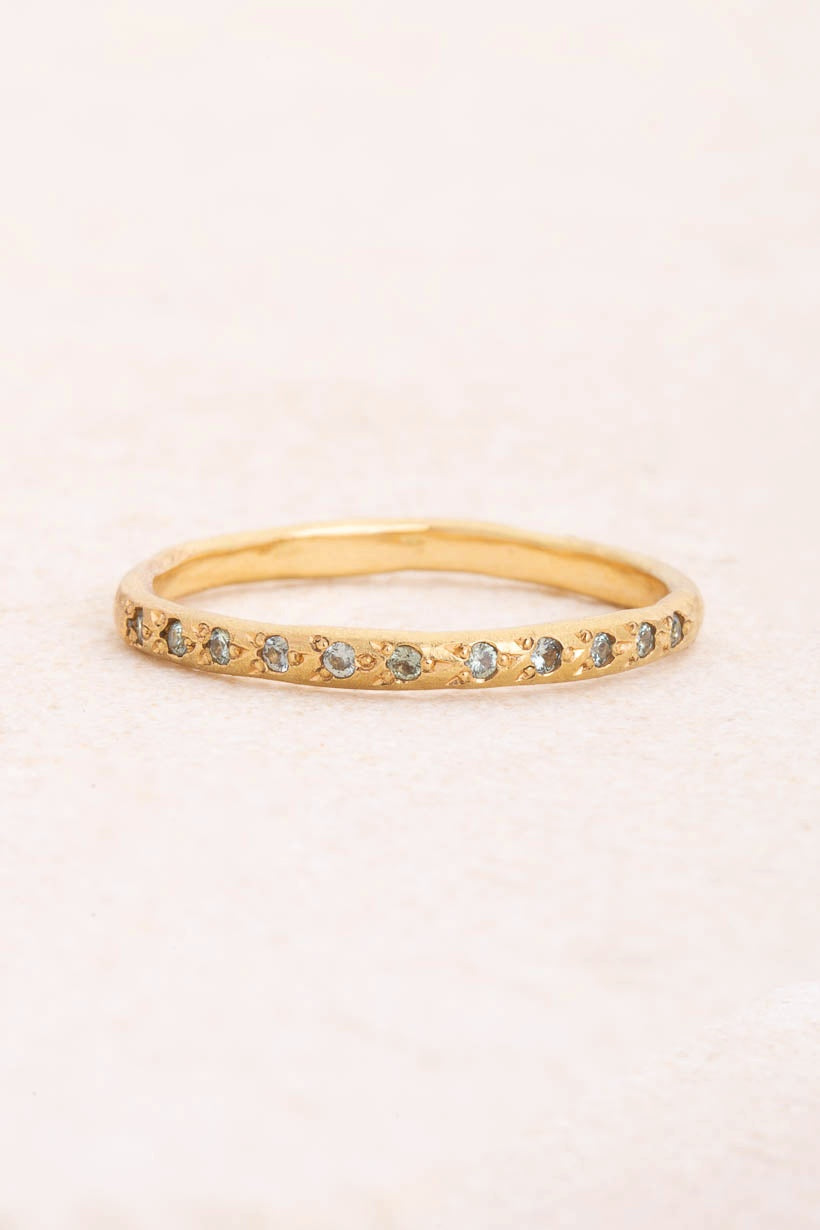 Flat lay of the Rosette ring with eleven flower-set light green Australian sapphires in textured recycled yellow gold