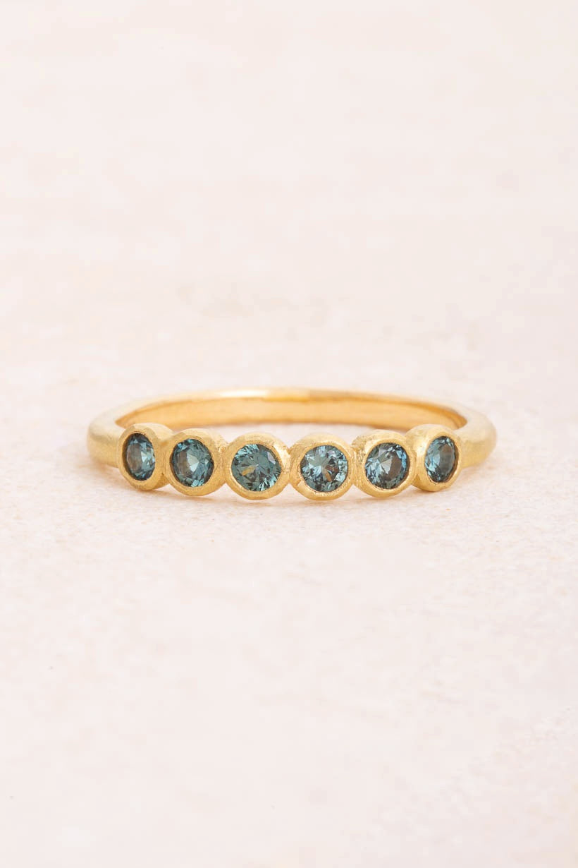 Gumnut wedding band with six teal blue Australian sapphires in textured bezel settings on a 1.9mm recycled gold band, Ada Hodgson