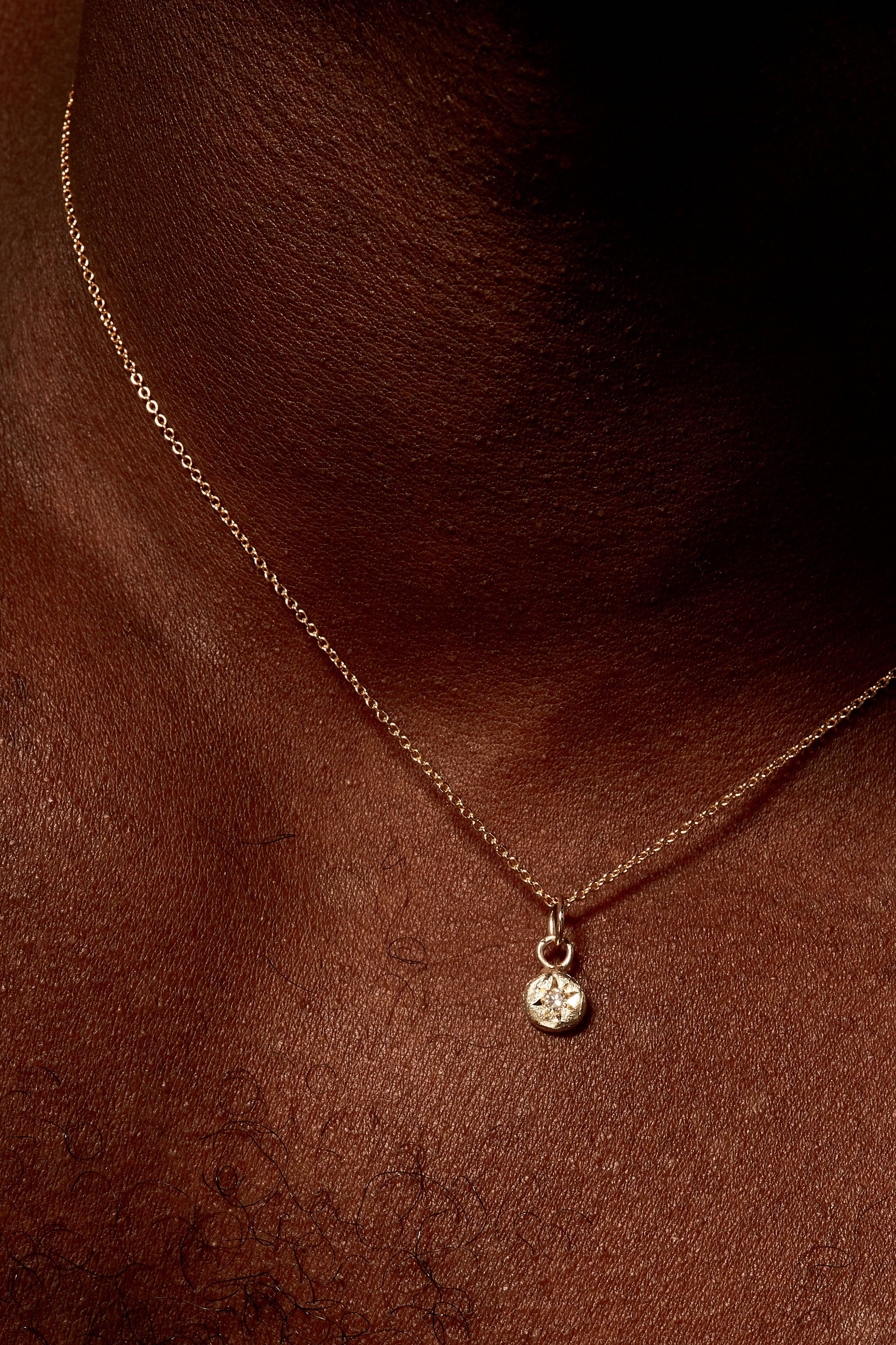 Close-up of diamond birthstone charm on gold chain