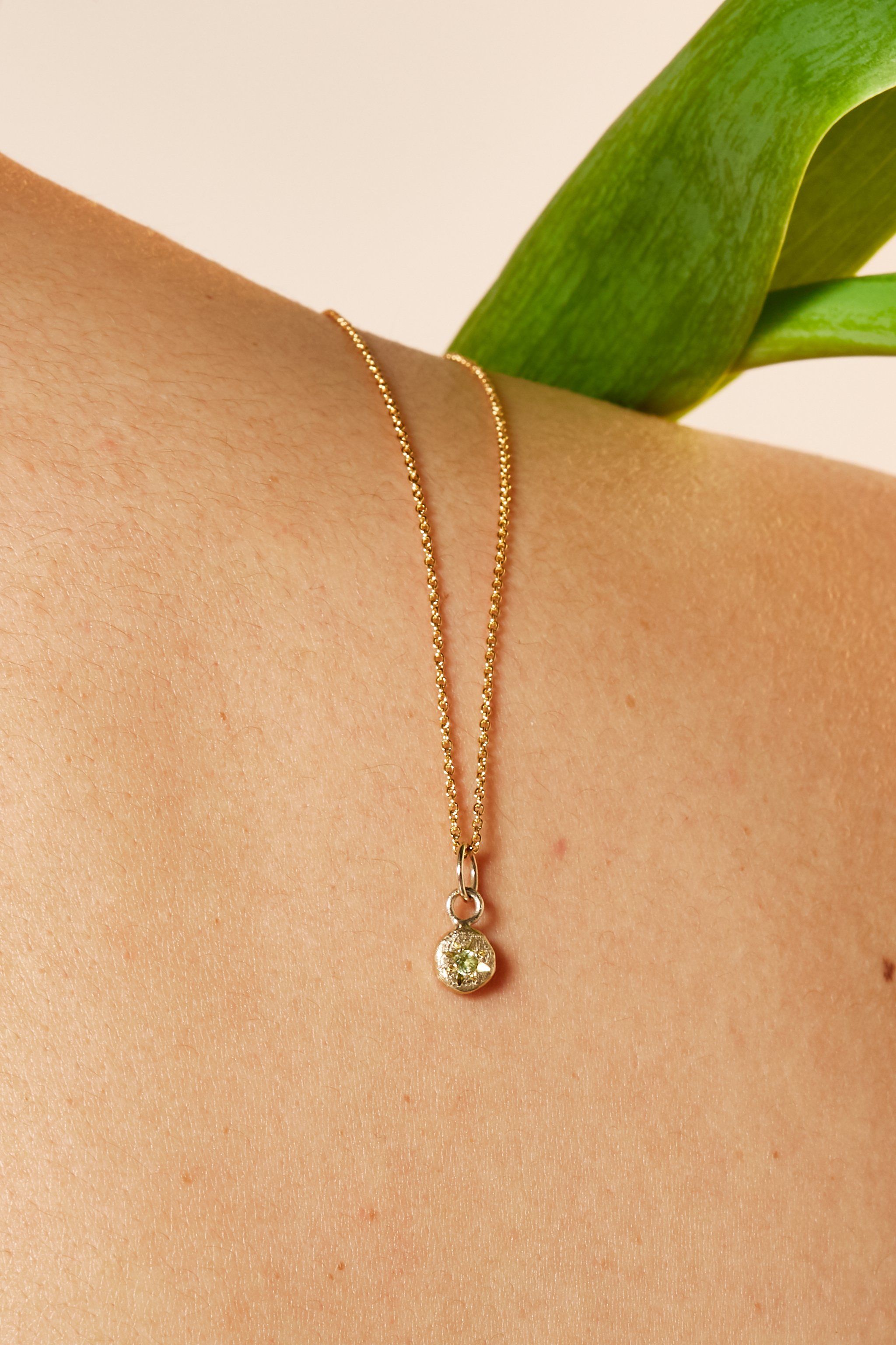 Close-up of peridot birthstone charm on gold chain