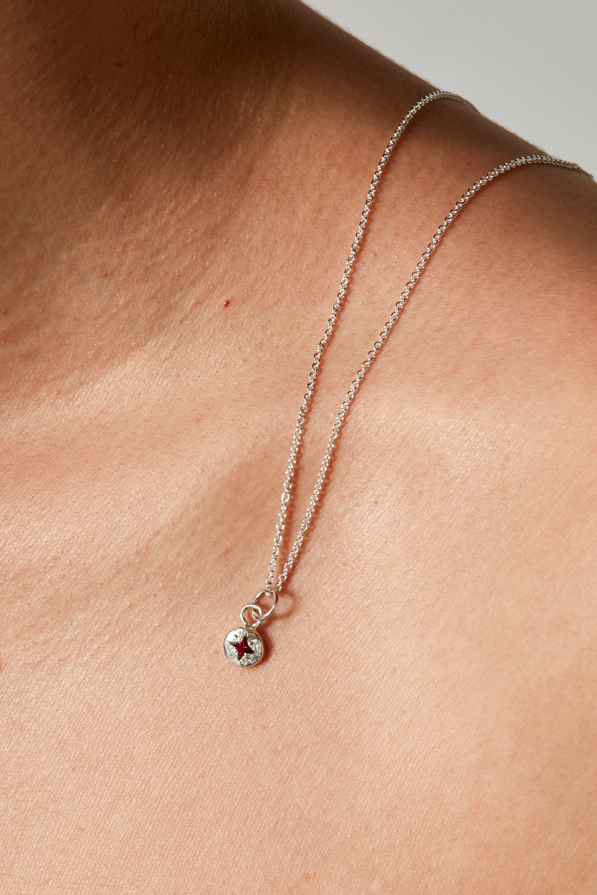 Close-up of ruby birthstone charm on silver chain