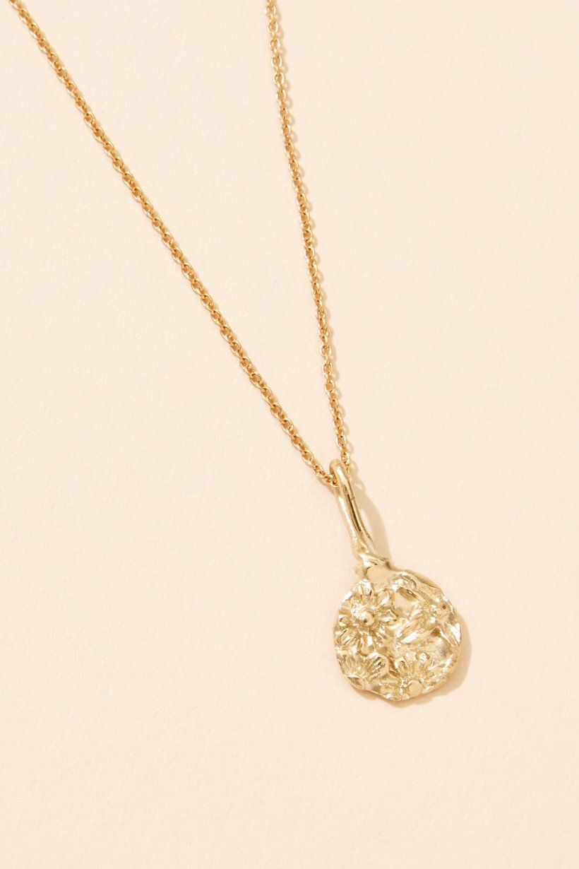A gold floral relic pendant necklace on a delicate 9kt gold chain.