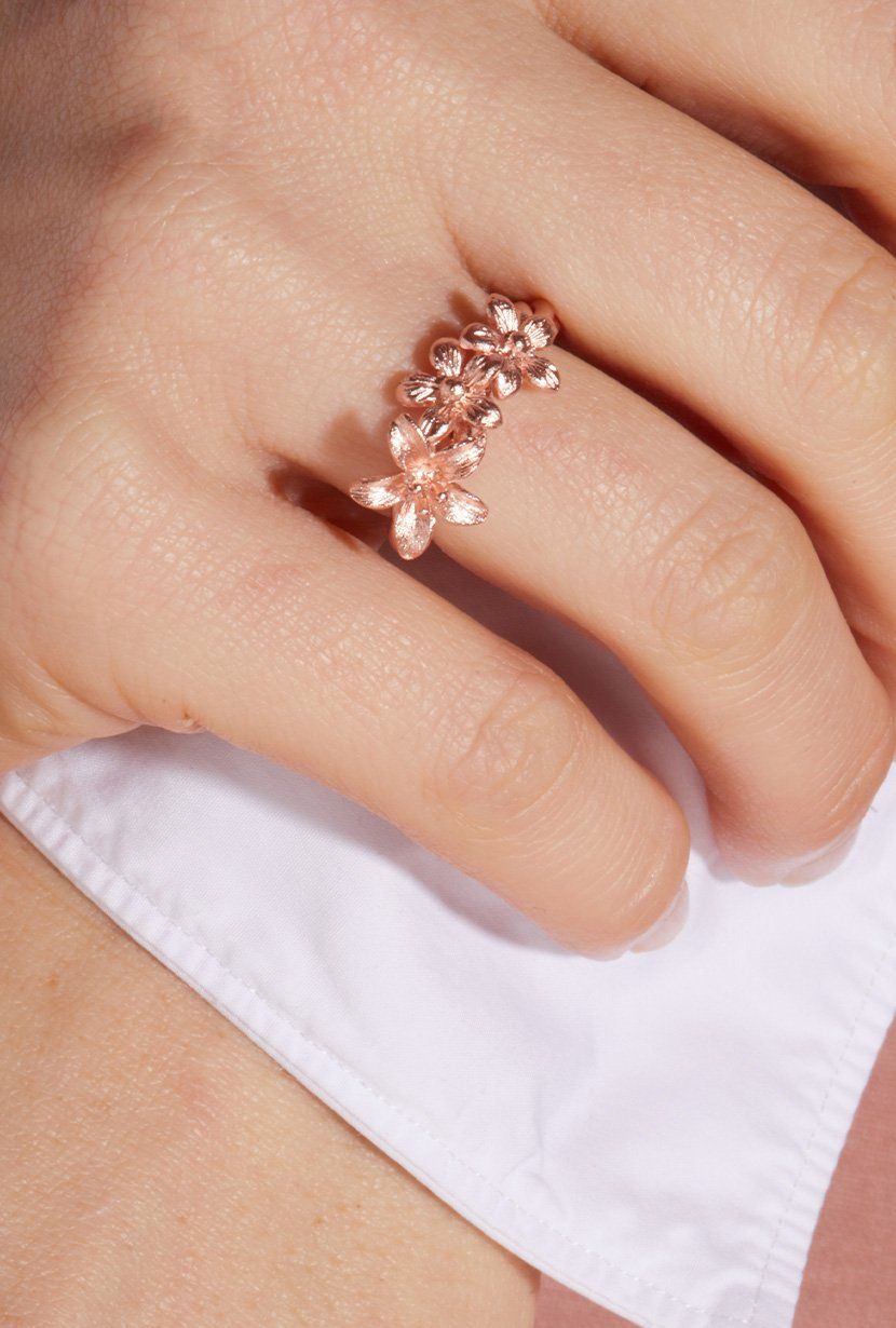 Rose Gold garland ring on models hand. Three wildflowers along a fine twisted ring band.