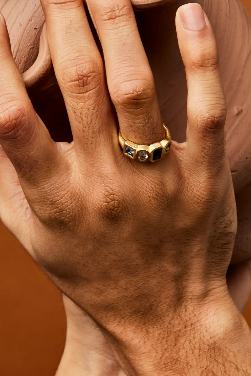 Angled view of Posy Ring showing deep blue, green, and light blue sapphires with central white diamond