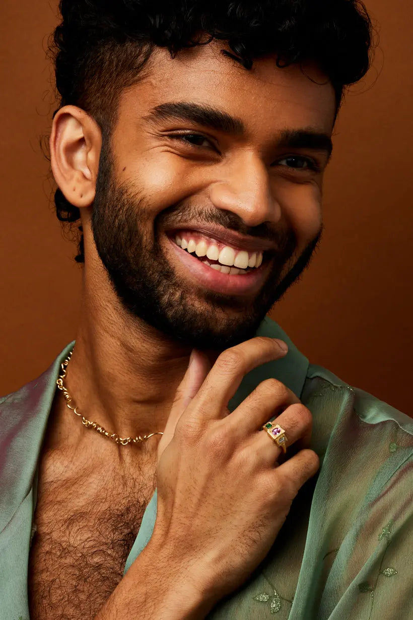 Smiling model wears golden curling tendril vine necklace with golden stepping stones ring.
