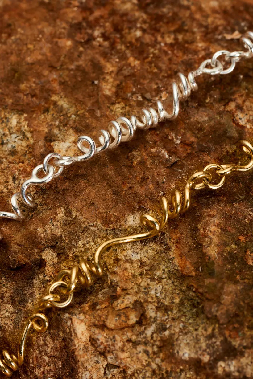 Sterling silver and gold tendril necklace on rock