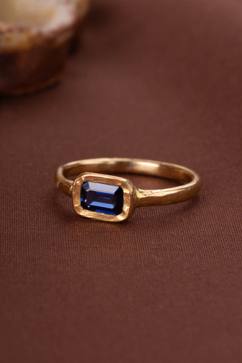 Gold ring with a blue gemstone on a brown background