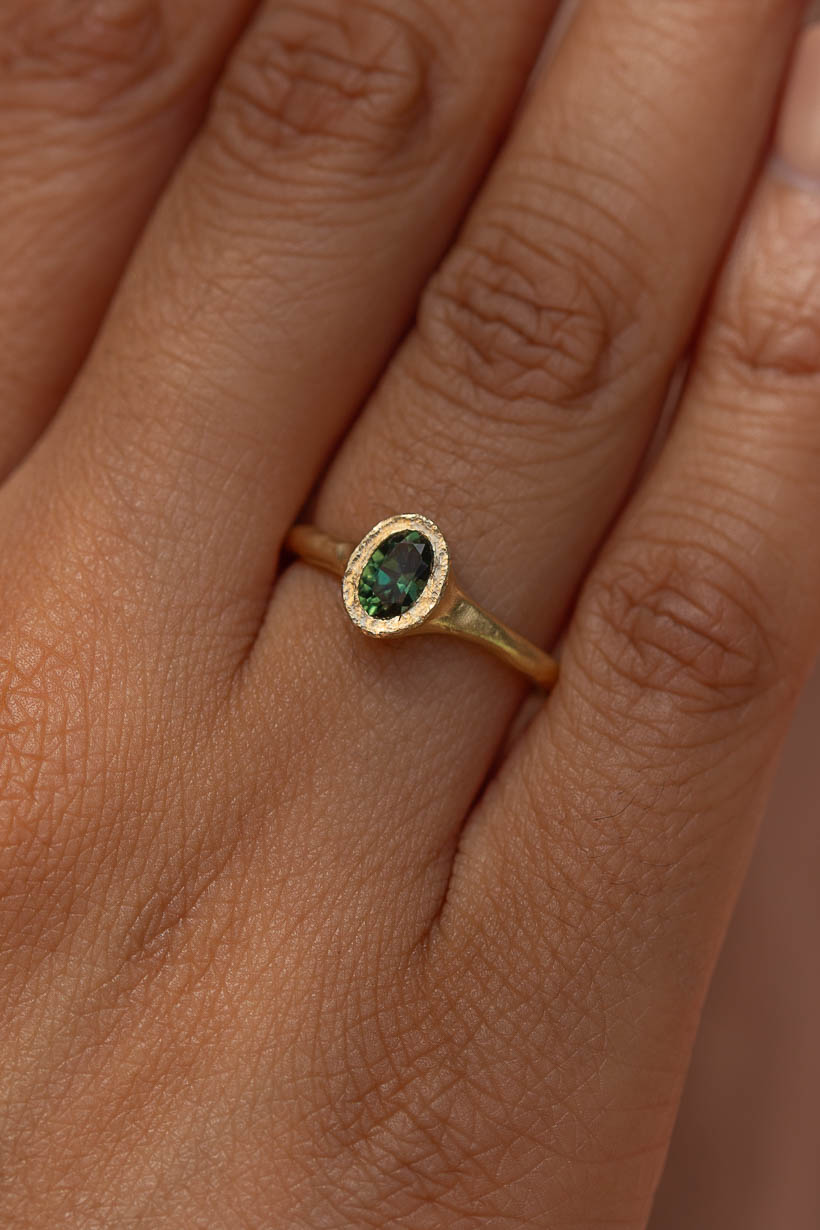 Close-up of the textured bezel setting on the Bower Ring in gold with a green Australian sapphire