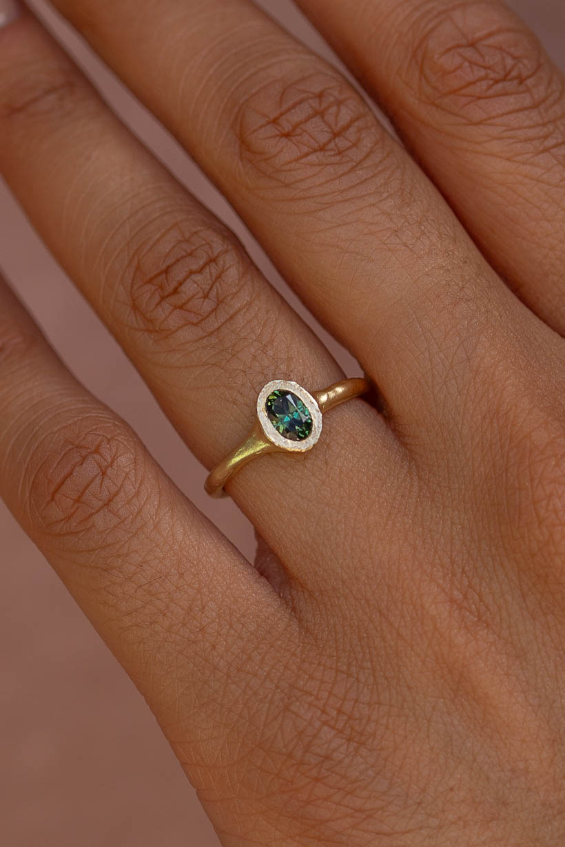 Close-up of the Bower Ring in gold with a green Australian sapphire, showing the textured bezel setting