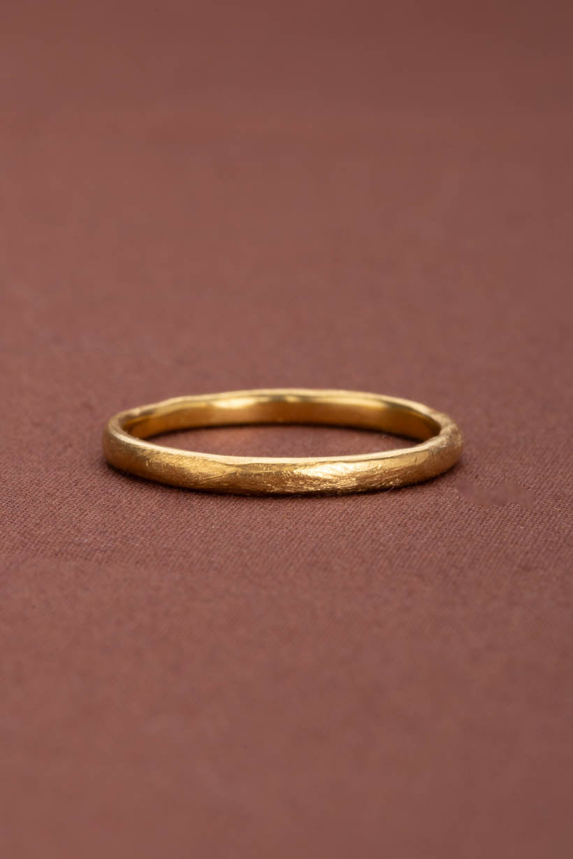 2mm wide softly textured gold breeze ring on brown fabric flatlay