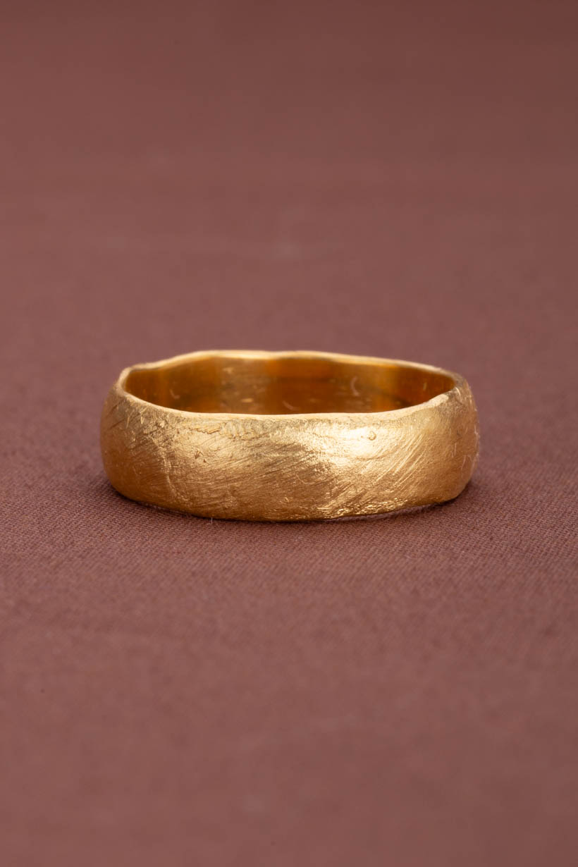 Gold ring on a brown background. 6mm lightly textured unique wedding ring. 