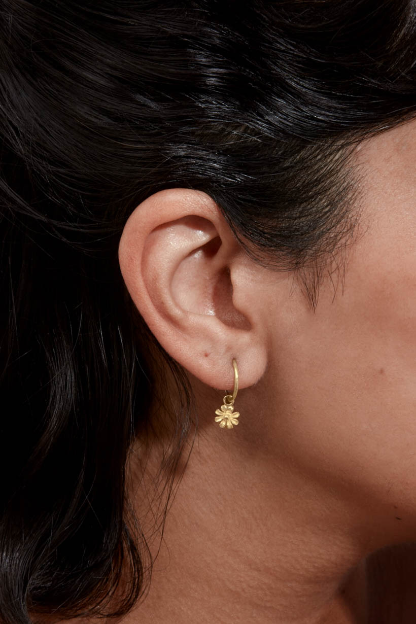 Close-up of 9ct yellow gold daisy sleeper earring worn on ear
