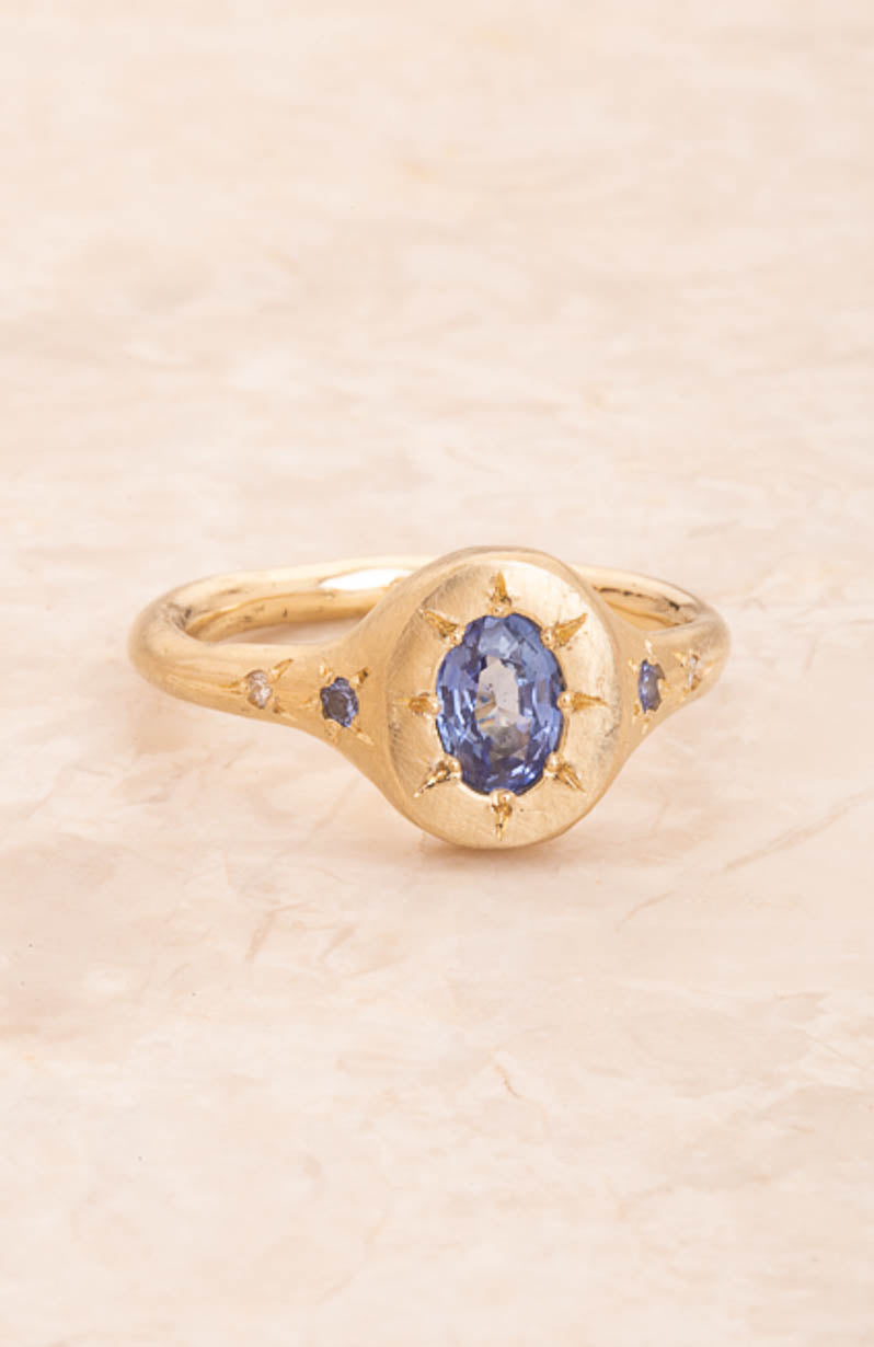 Gold ring with a blue gemstone on a beige background