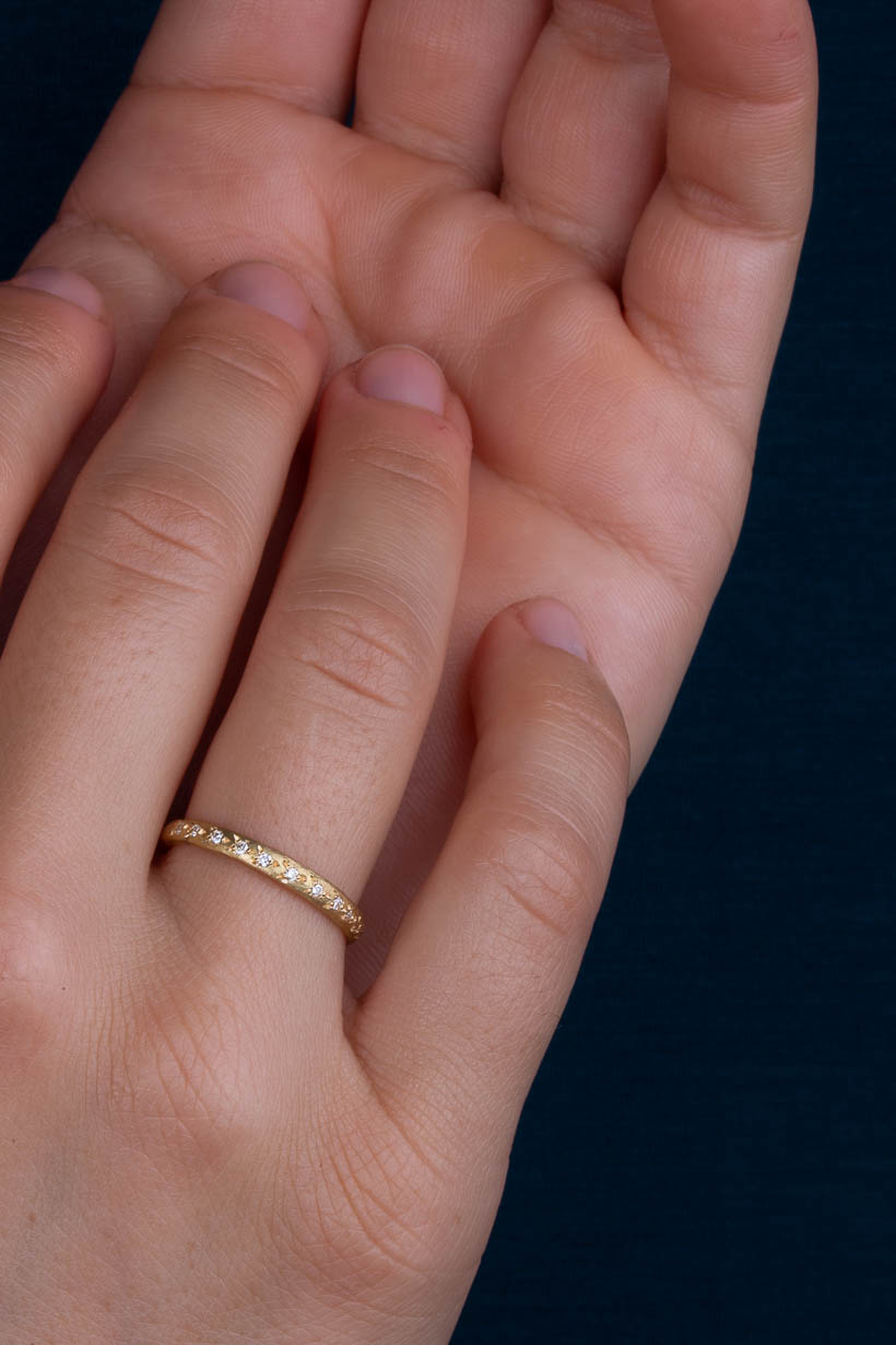 Model wearing gold Rosette Ring with eleven white diamonds in natural light