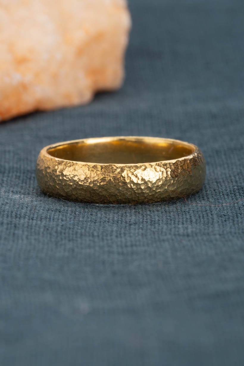 Gold ring with a textured surface on a blue fabric background