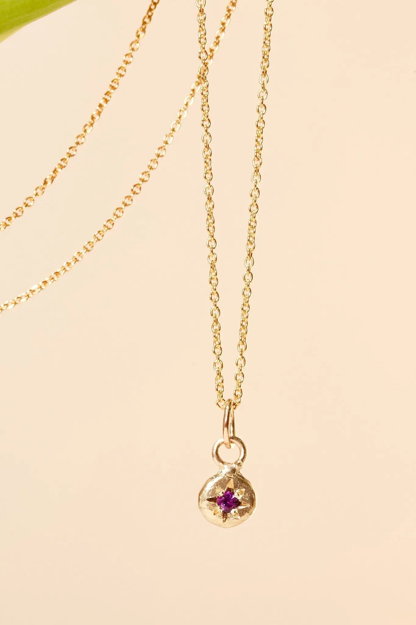Close-up of amethyst birthstone charm on gold chain