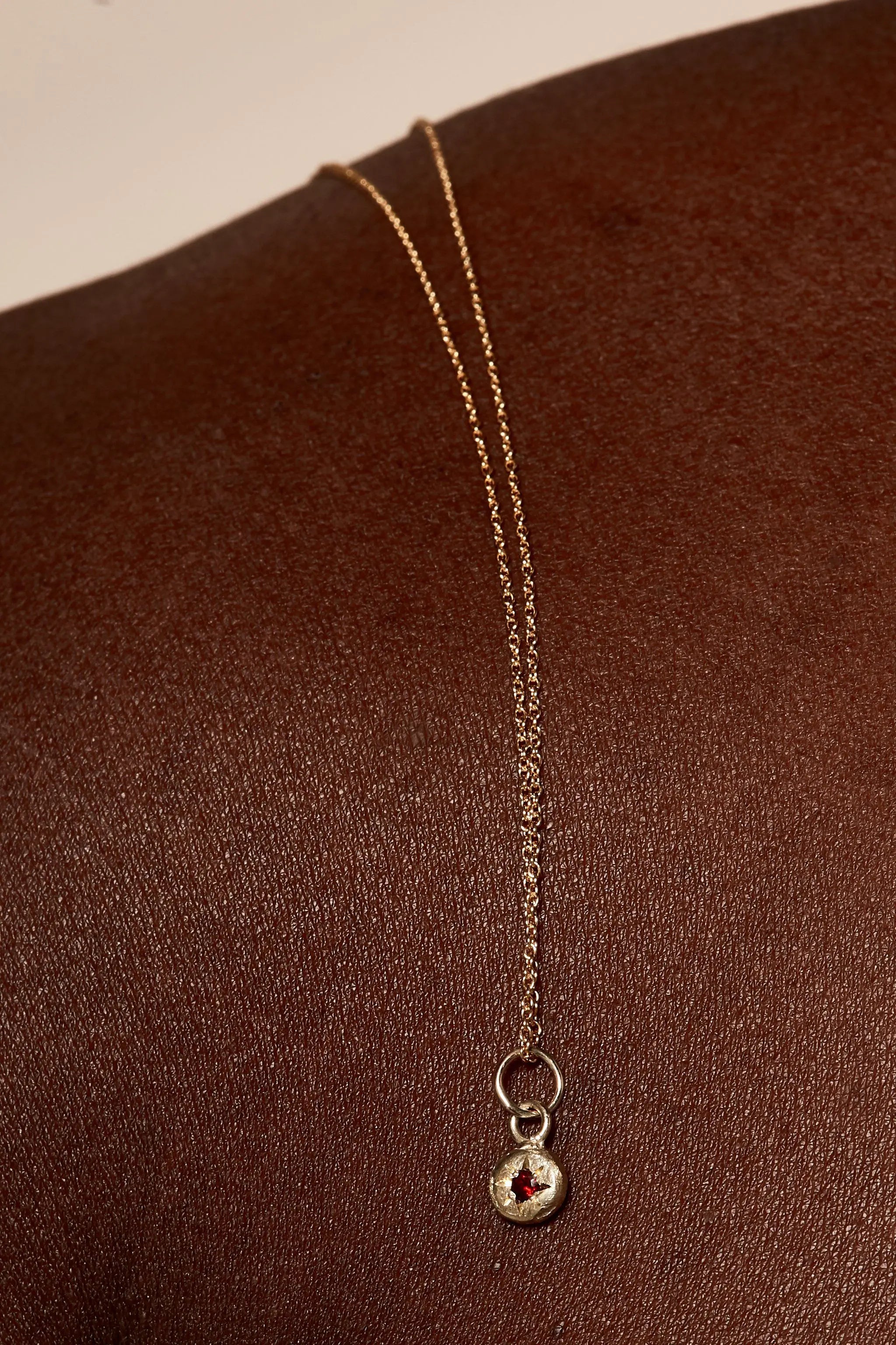 Close-up of garnet birthstone charm on gold chain