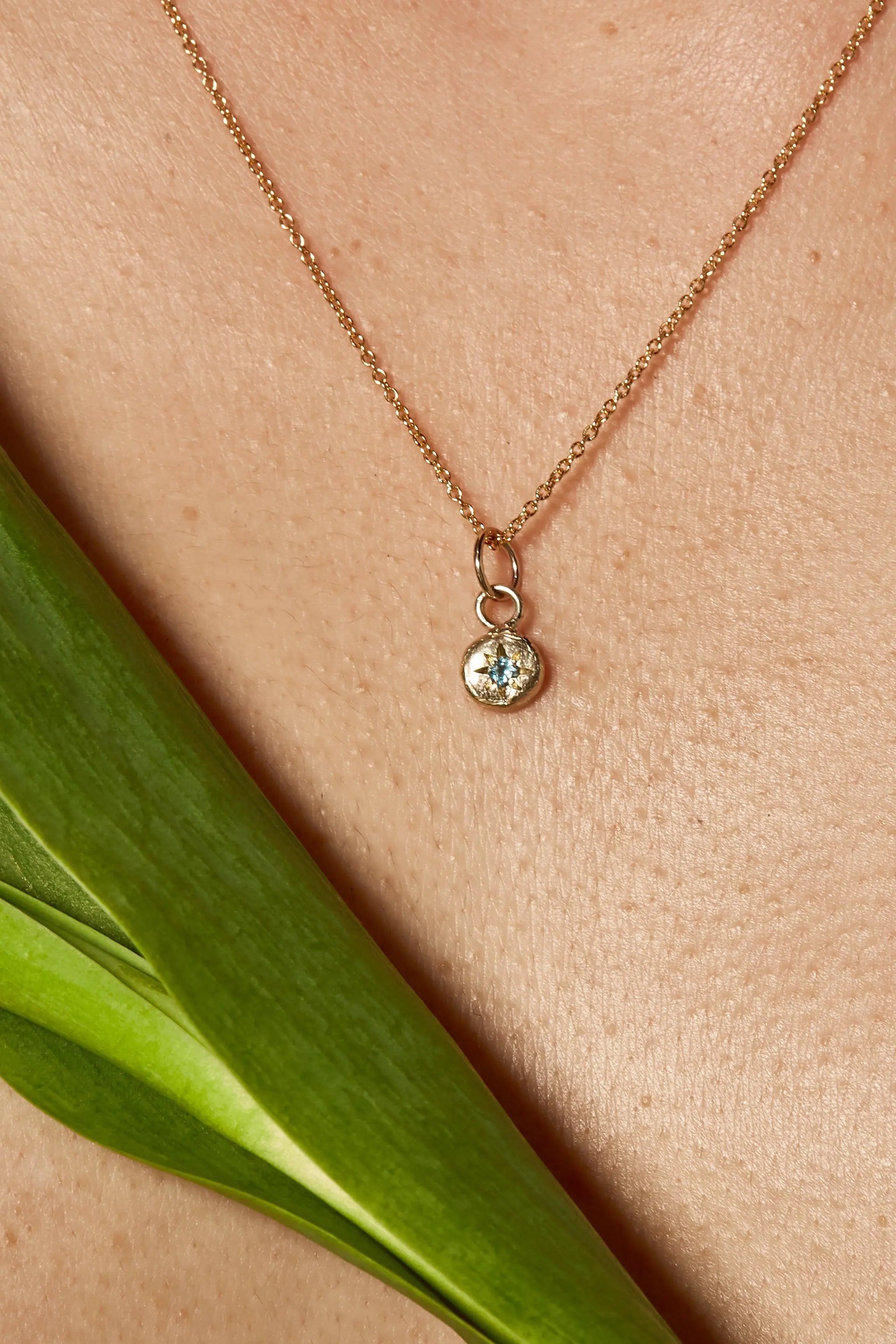 Close-up of aquamarine birthstone charm on gold chain