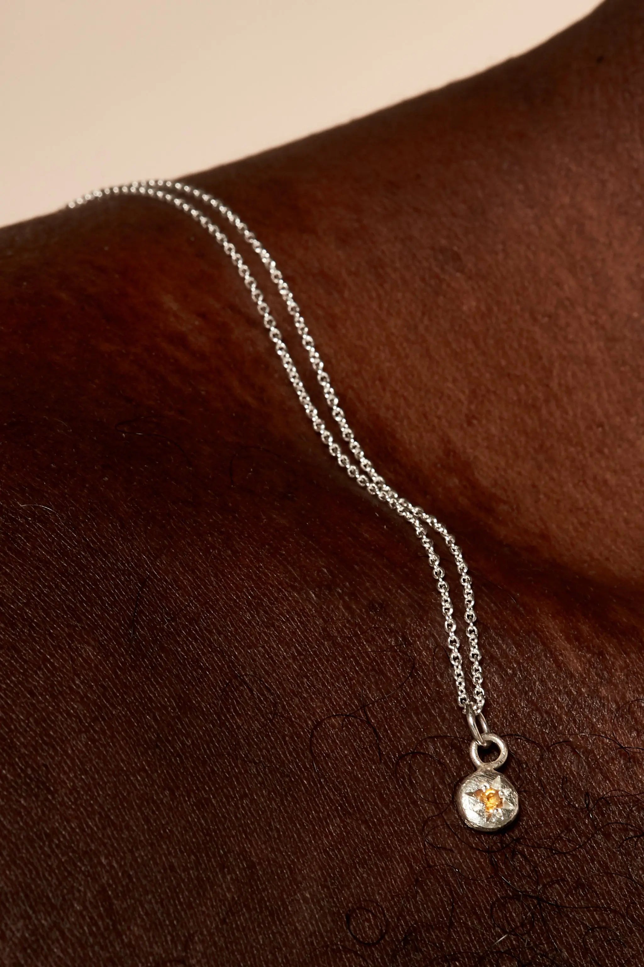 Close-up of yellow citrine birthstone charm on silver chain