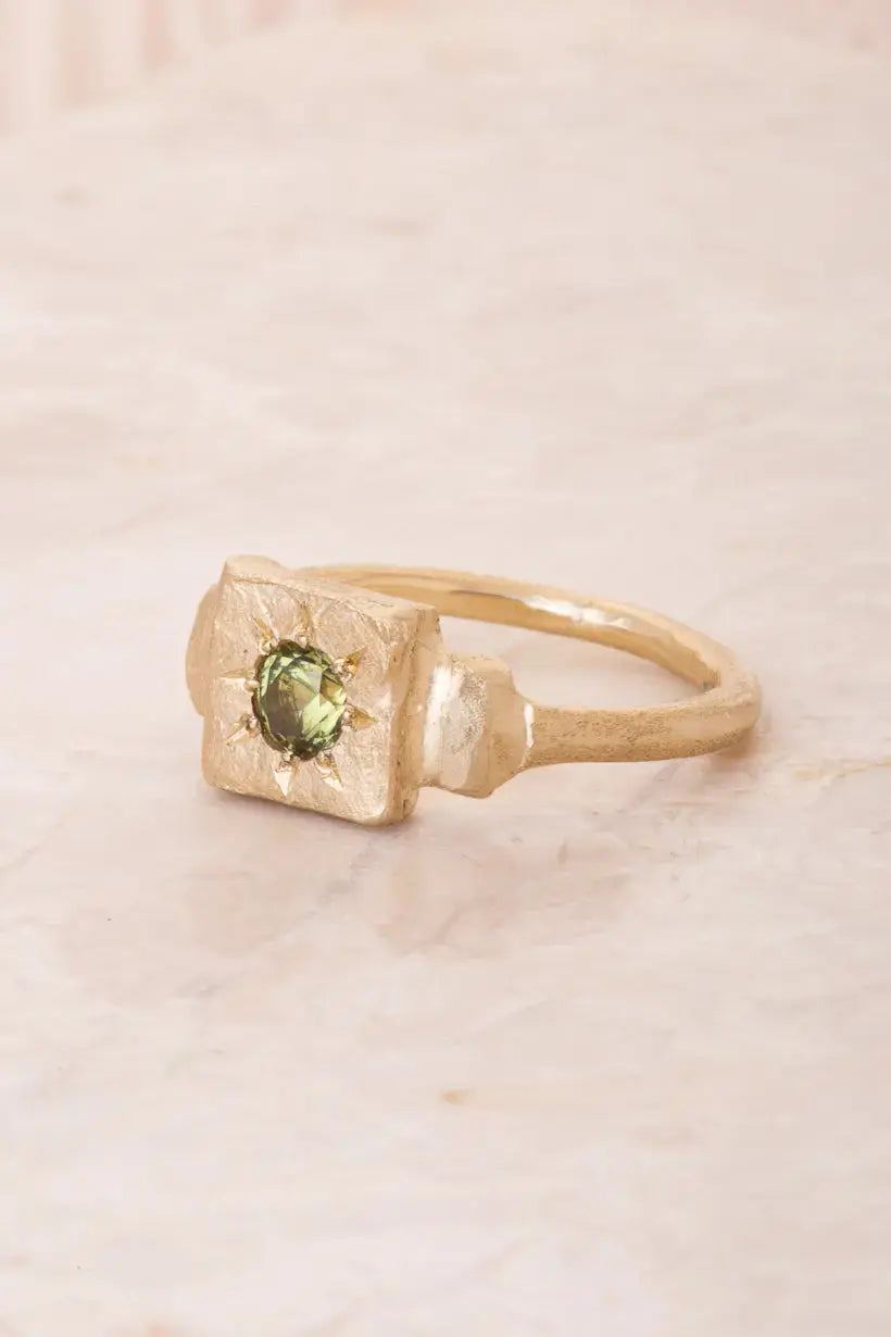 Side view of a perfectly imperfect square shaped gold signet ring star set with a vibrant green australian sapphire. Showcasing the textured side details and ring band. 