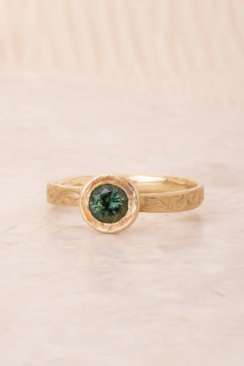 A 9kt yellow gold ring with a .75 carat green Australian sapphire center, designed to be stacked, placed on a neutral background.