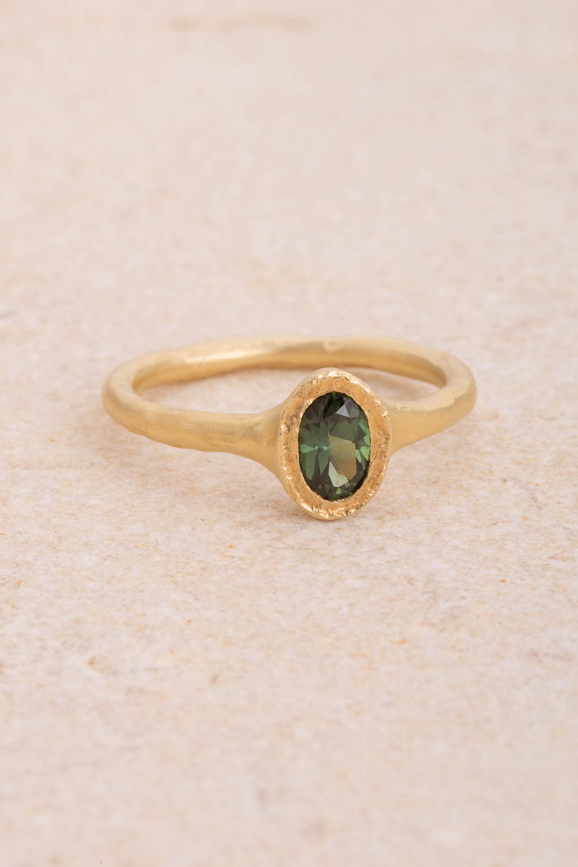 Bower engagement ring with an ethically sourced green Australian sapphire set north–south in a sculptural textured bezel on an organic band, handmade in Melbourne from recycled gold, front view on limestone