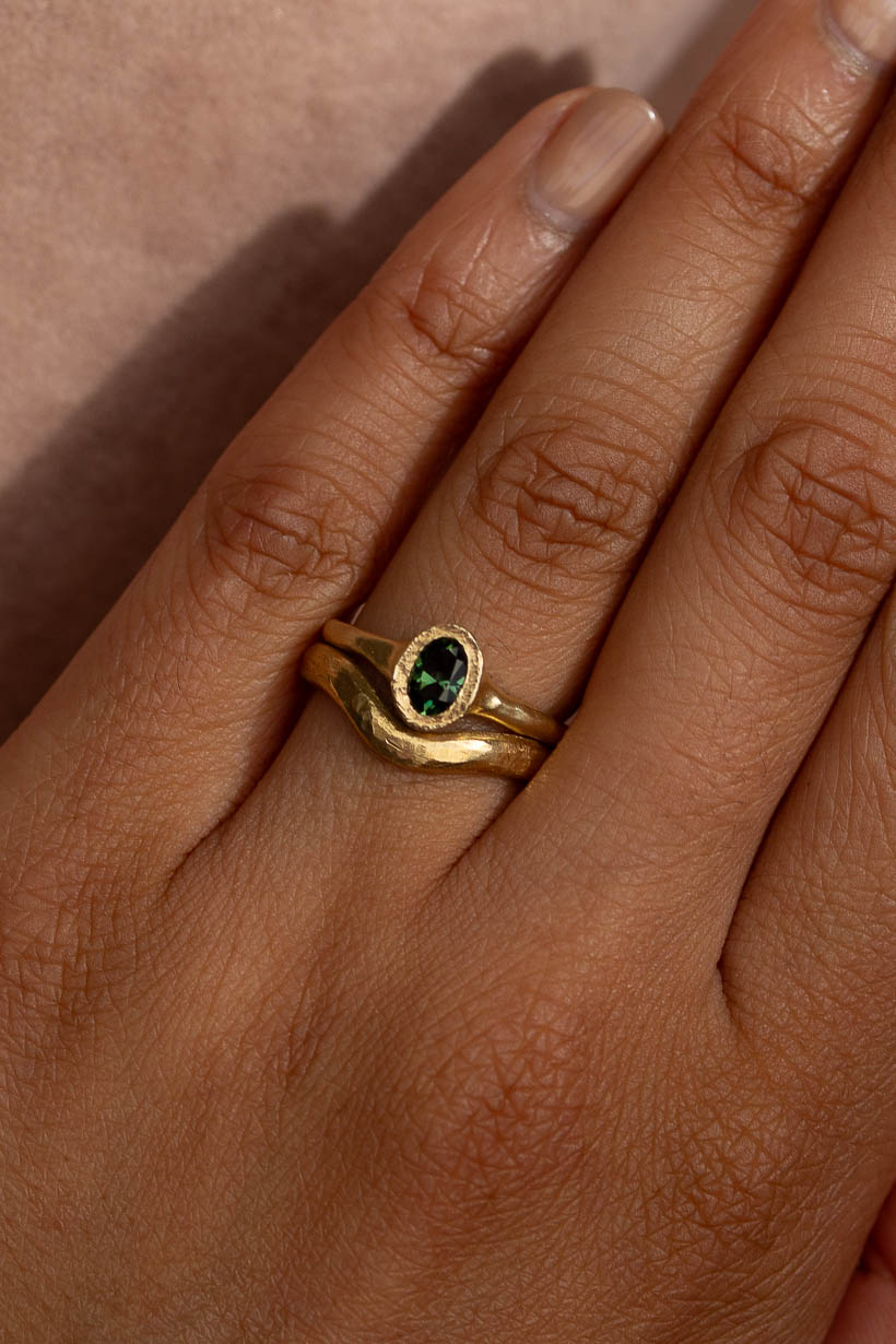 Hand wearing the Bower engagement ring with the 3mm curved Breeze wedding ring sitting snugly around its green Australian  sapphire