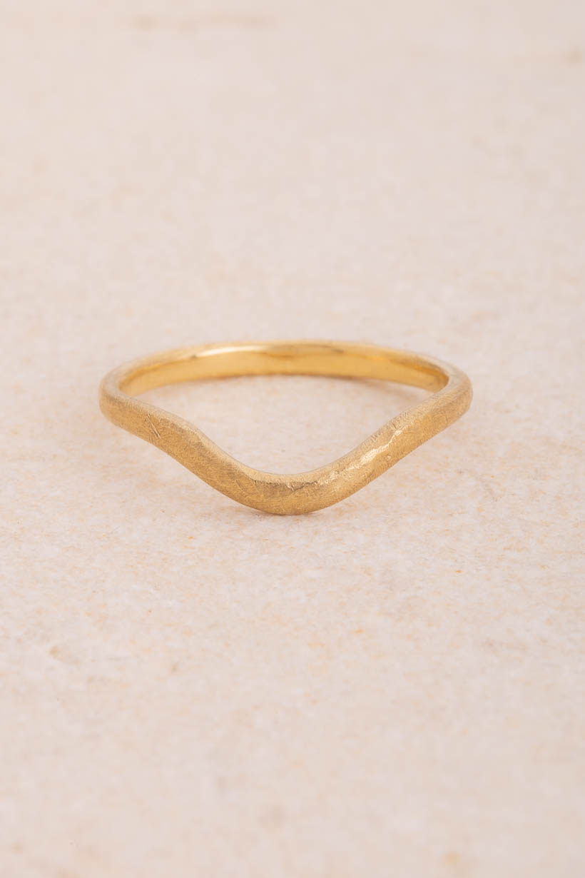 Curved Breeze 2mm fitted wedding band in textured recycled gold, gently arched to sit snugly beside an engagement ring, handmade in Melbourne, front view on limestone
