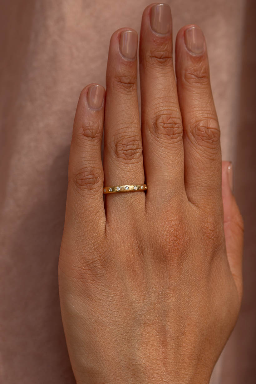 Dewfall diamond eternity ring worn on the hand, a textured gold wedding band with flush set white diamonds, handmade in Melbourne by Ada Hodgson