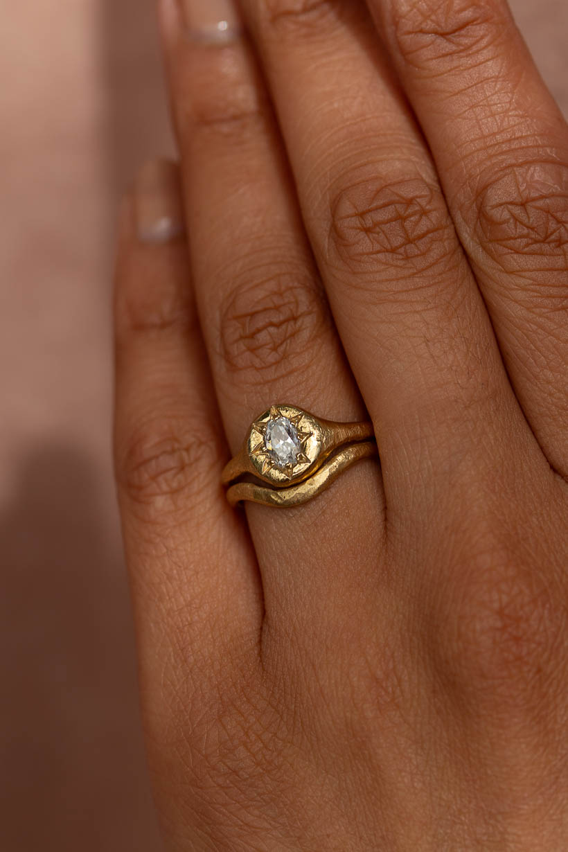 Monet's Garden oval diamond engagement ring in recycled yellow gold worn on hand stacked with curved 2mm Breeze wedding band 