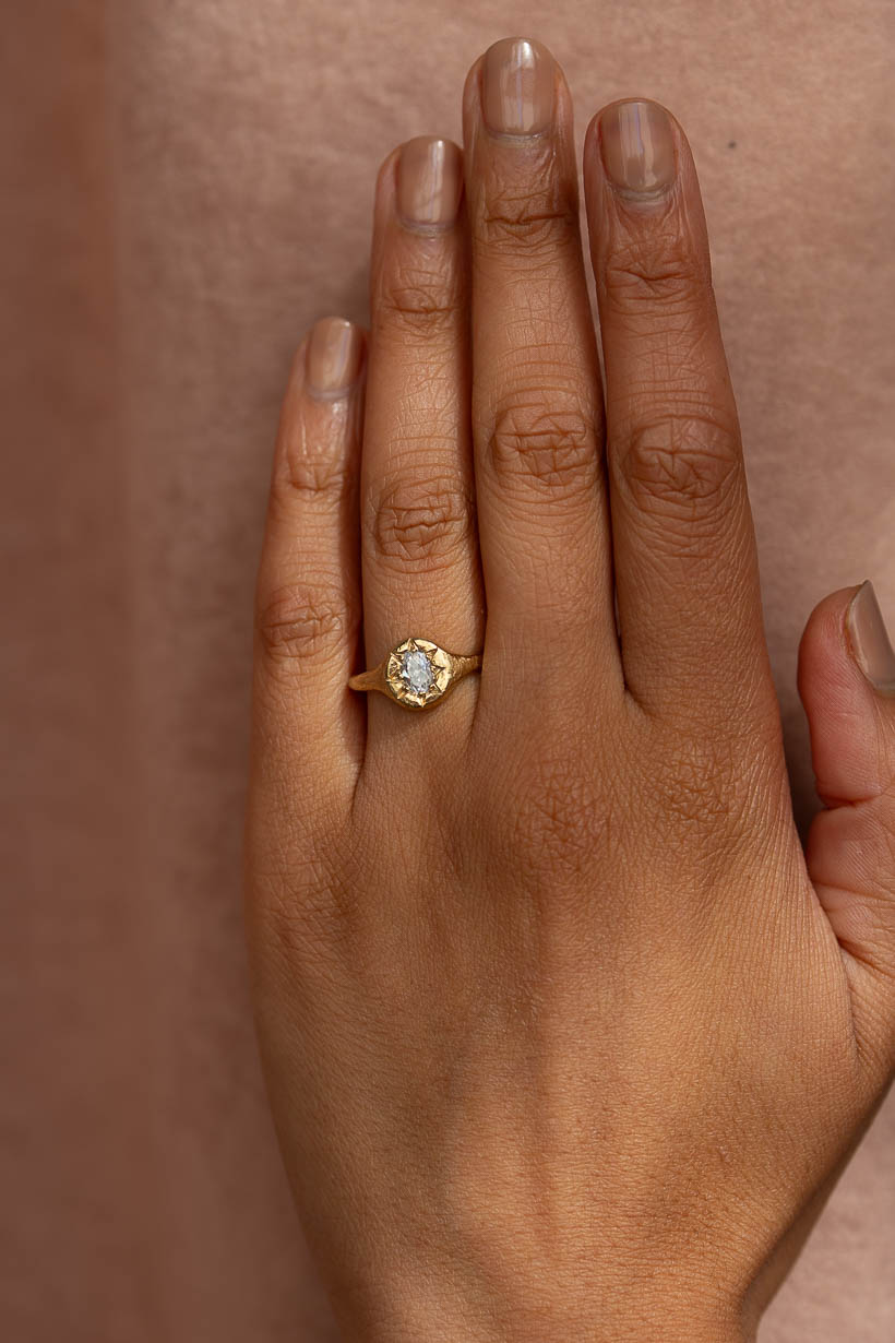 Monet's Garden oval diamond engagement ring in recycled yellow gold worn on hand.