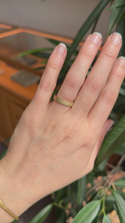 Textured gold wedding ring, the inures ring, on hand. 