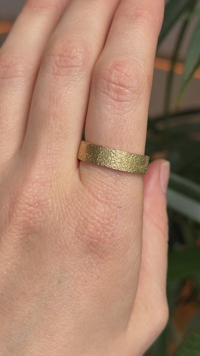 Textured gold wedding ring on models hand