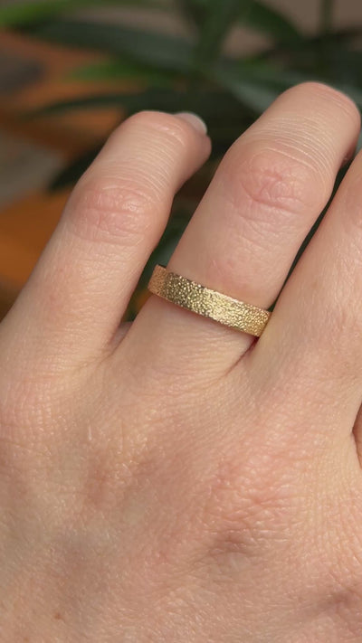 Close up video of textured citrus ring, a gold wedding band on hand. 