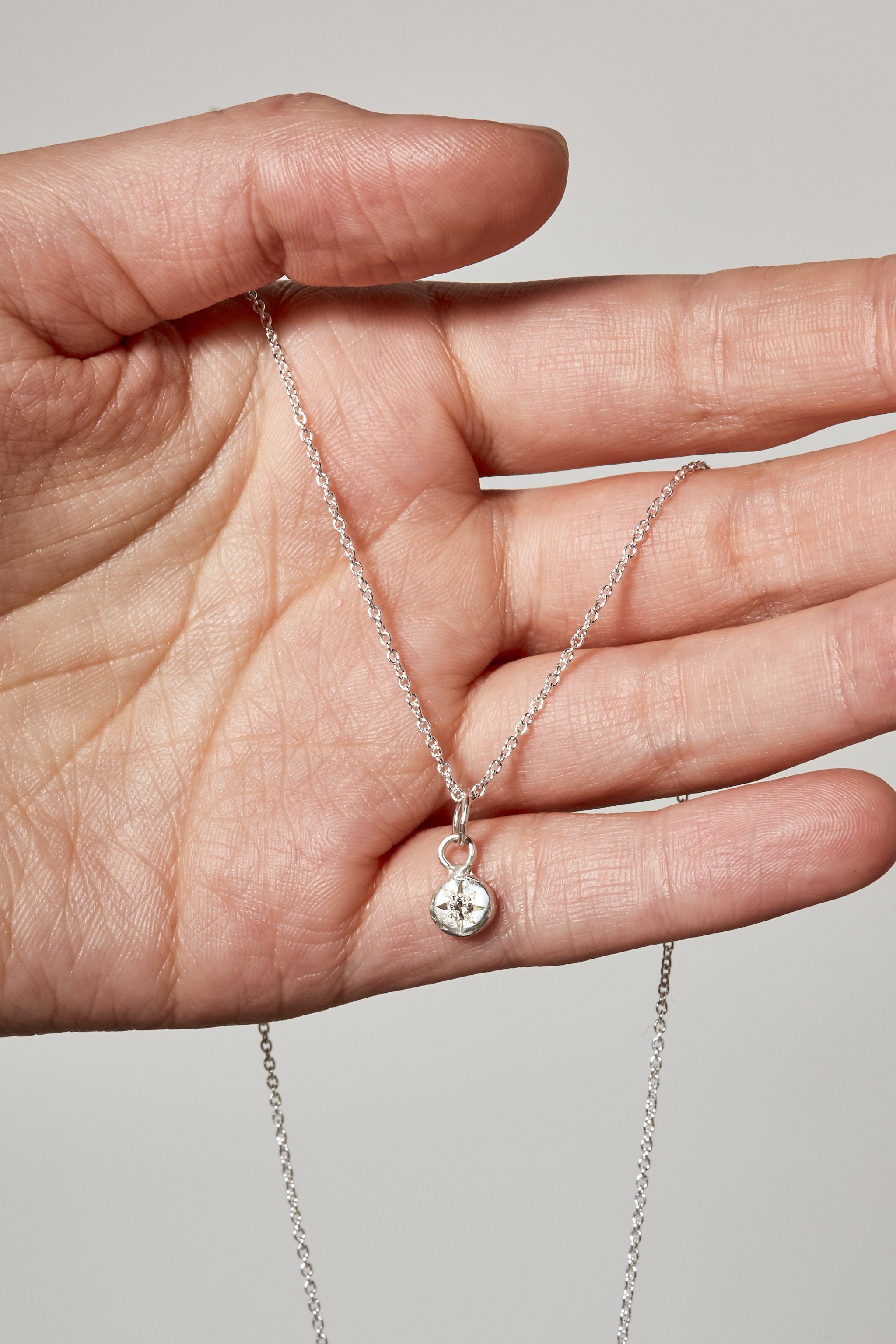 Close-up of diamond birthstone charm on silver chain