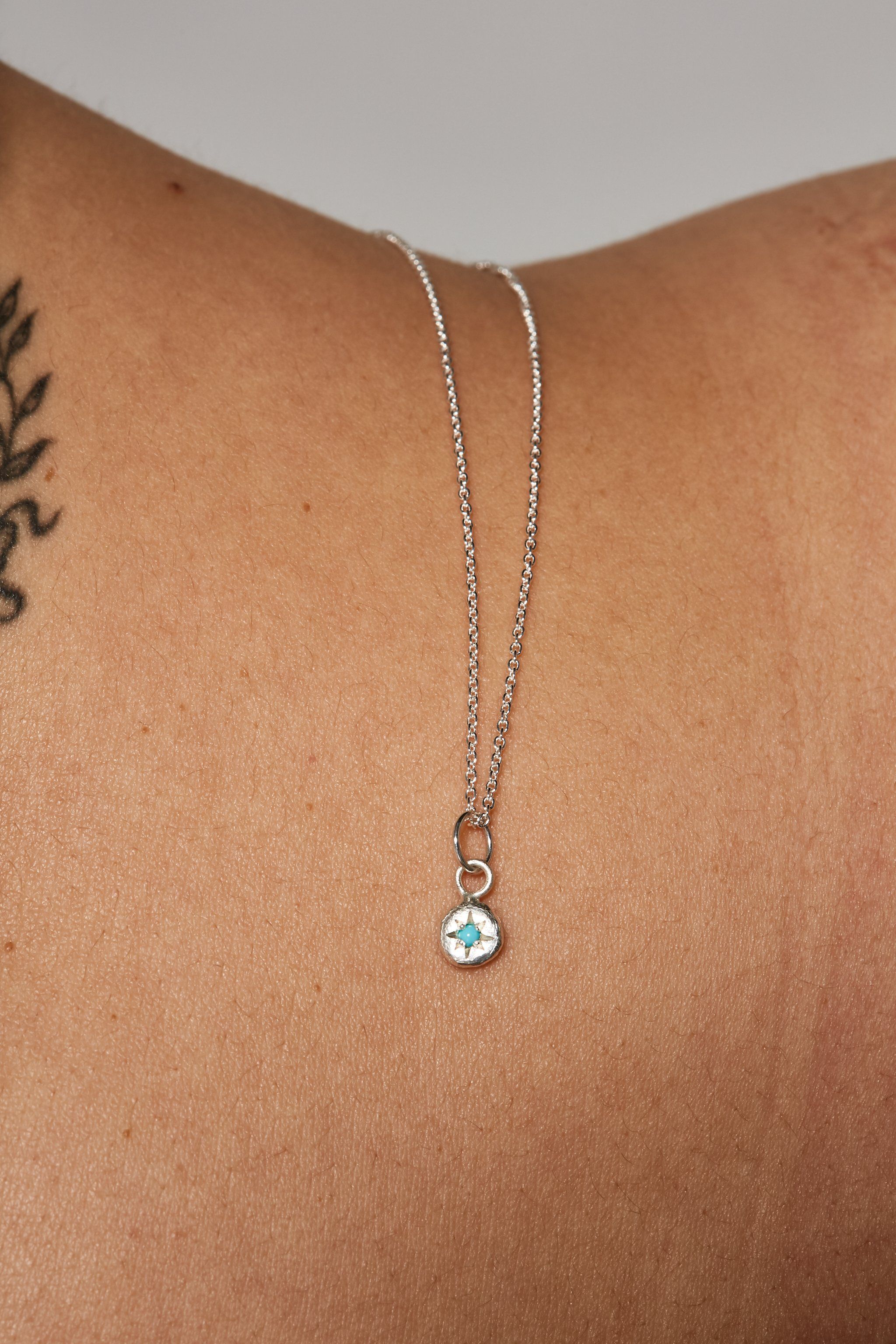 Close-up of turquoise birthstone charm on silver chain